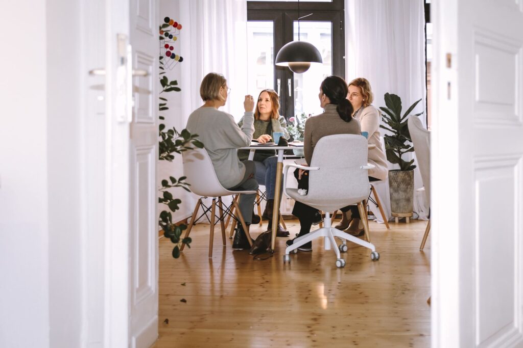 Unternehmerinnen sitzen an einem hellen Tisch und arbeiten zusammen