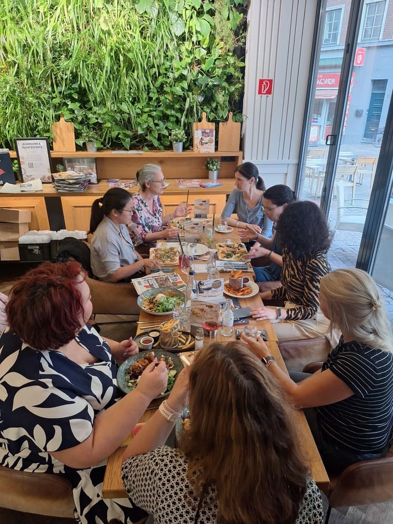 Unternehmerinnen sitzen beim BizzConnect an einem langen Tisch in einem Café in Aachen