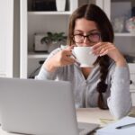 Frau am Laptop mit einer Kaffeetasse
